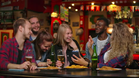 Eine-Große-Gruppe-Von-Freunden-Sitzt-In-Der-Bar-Am-Tisch,-Lacht,-Plaudert-Und-Trinkt-Bier.